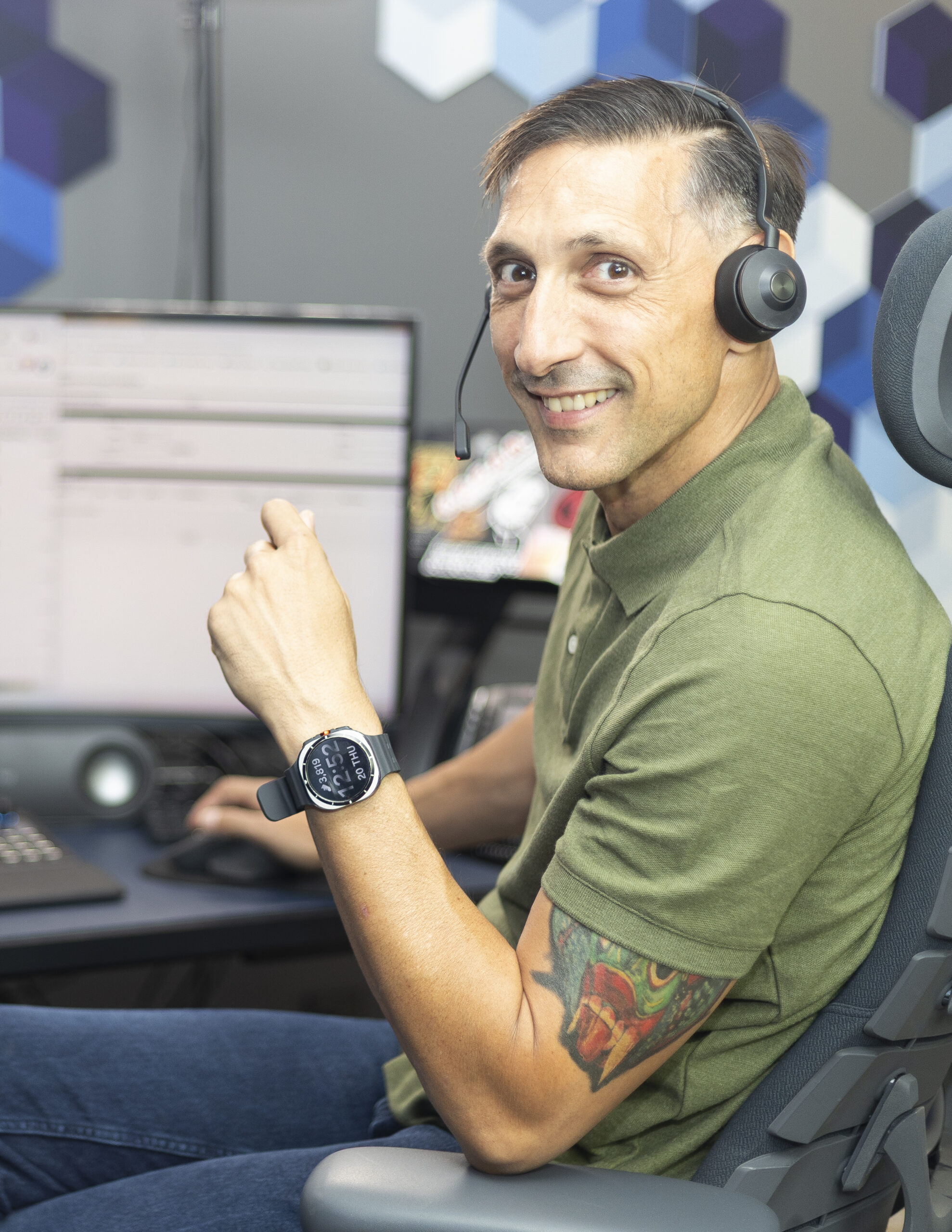 Jarrod Roberts at his desk in a headset, turning from the monitors to face the camera.