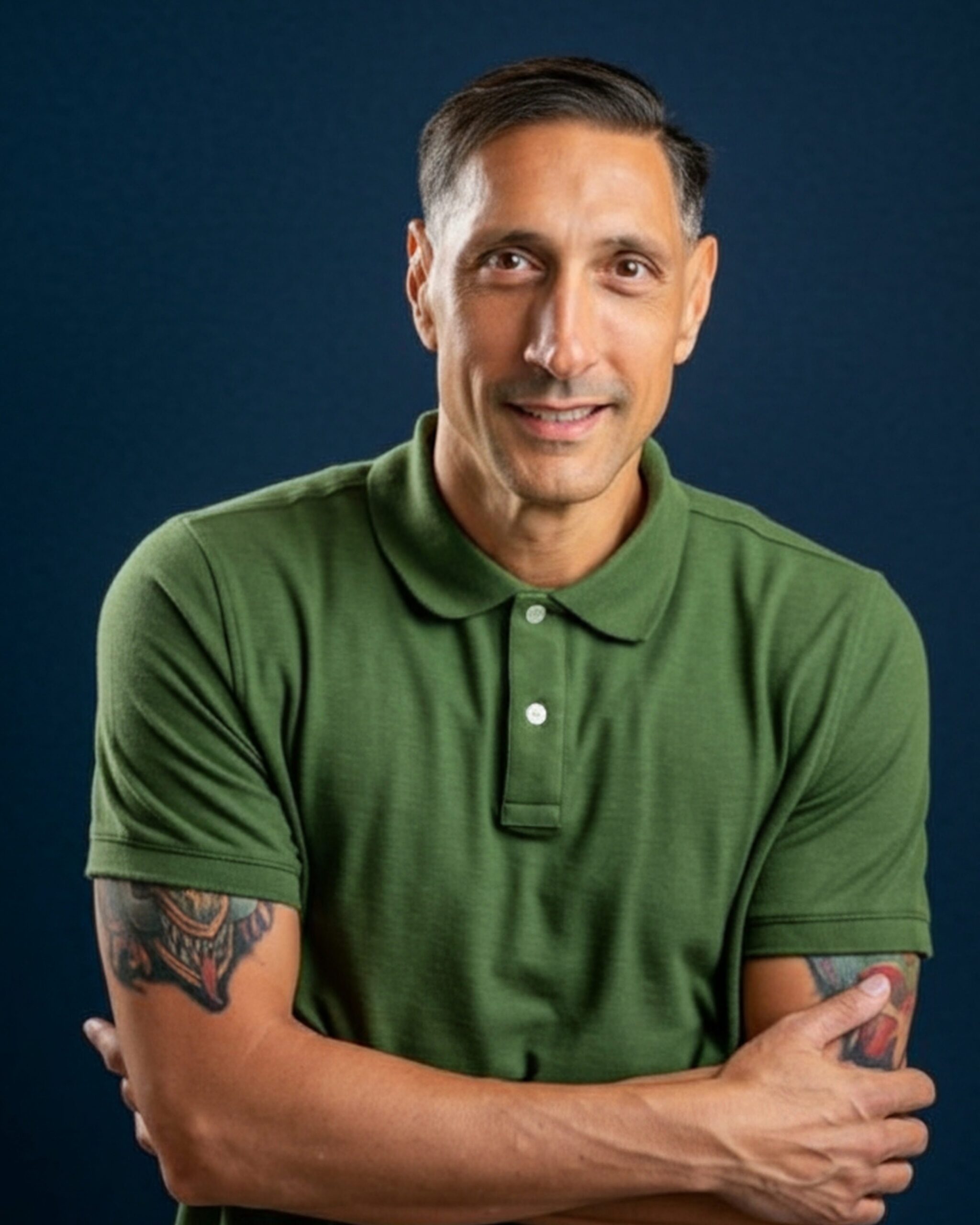 Jarrod Roberts, arms folded, in a green polo shirt against a deep navy background.