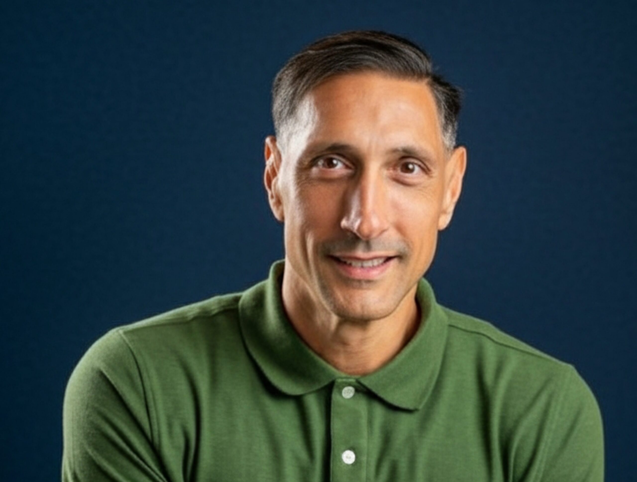 Jarrod Roberts, arms folded, in a green polo shirt against a deep navy background.