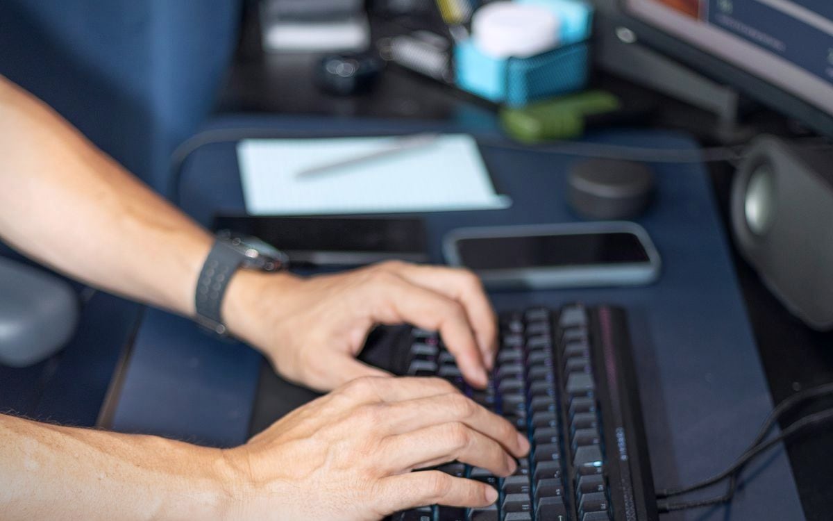 Hands typing on a backlit keyboard at a home sales desk.