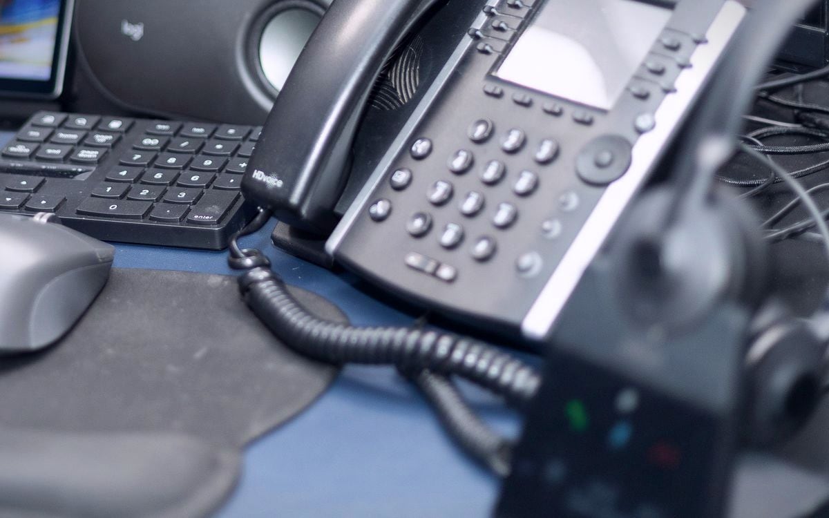 A desk phone and headset base at a home sales desk.