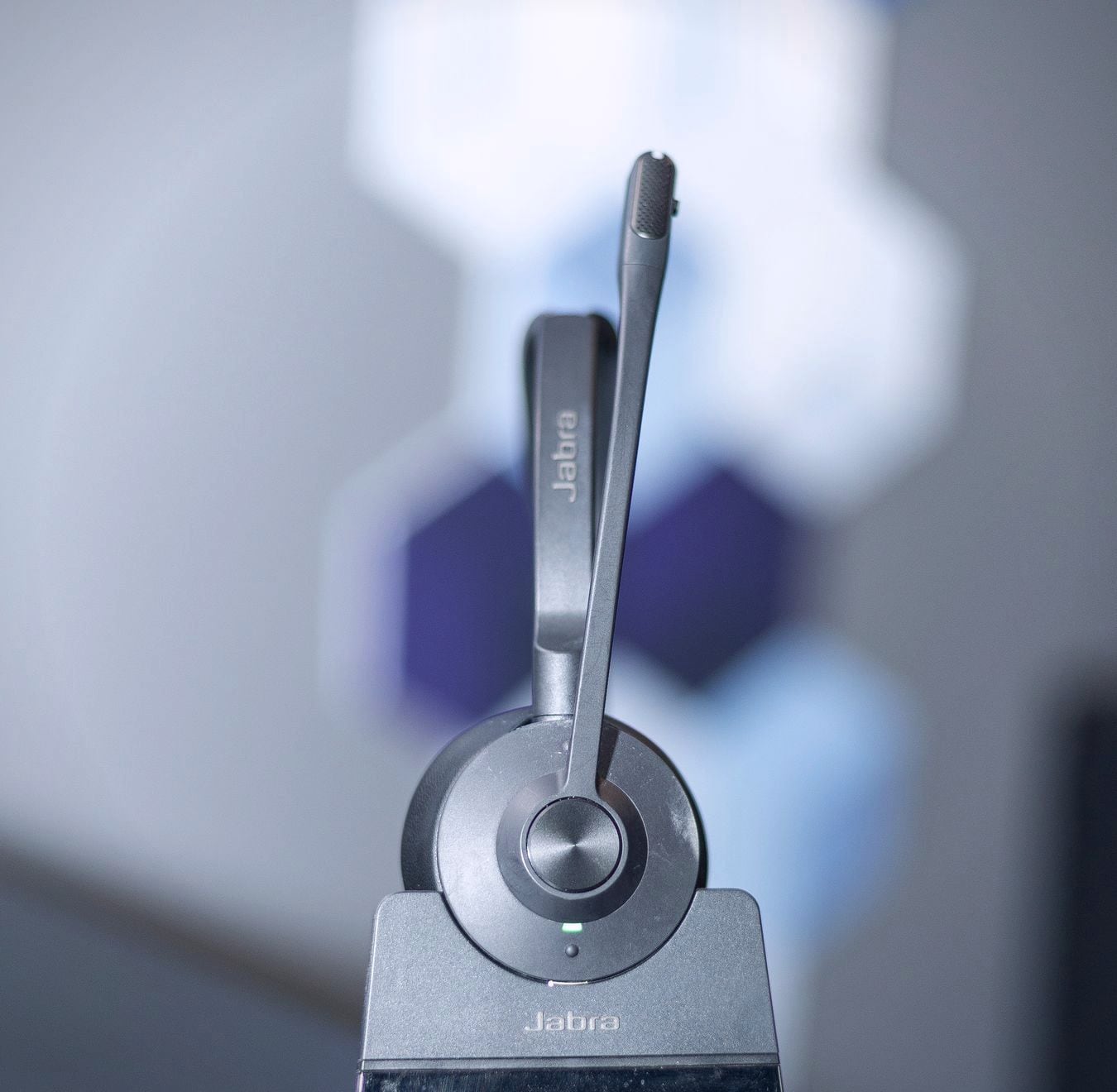 A wireless headset standing on its charging base, shot close with a soft background.