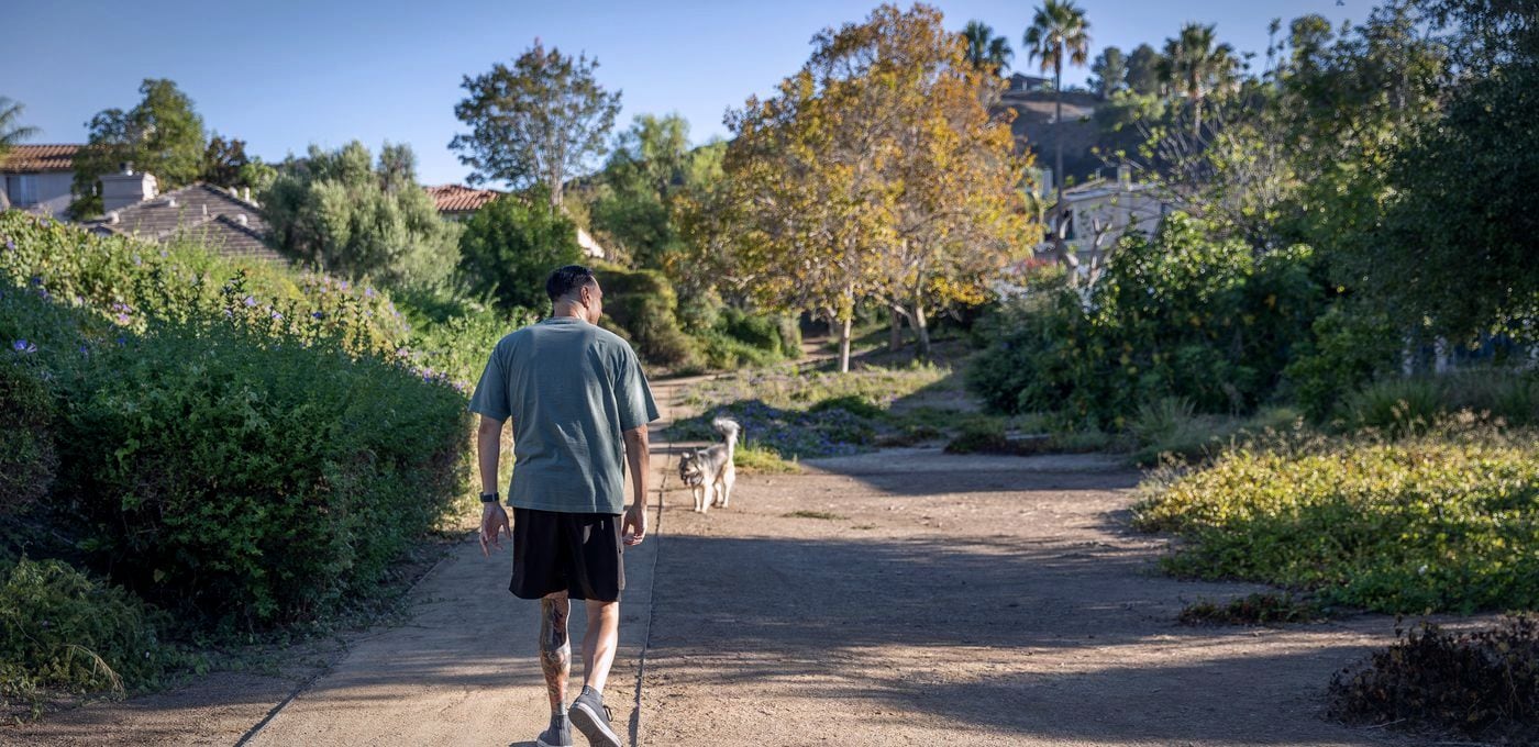 Jarrod Roberts walking away down a quiet garden path in early morning light.