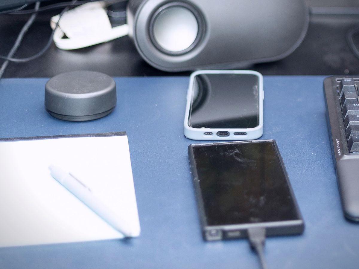 A notepad and pen beside two phones on a home sales desk.